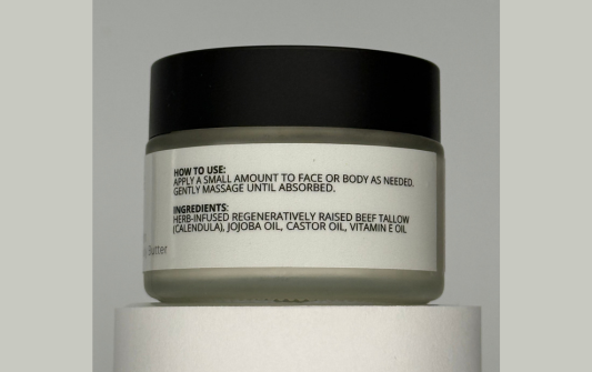 Skincare jar with black lid and white label on a gray background