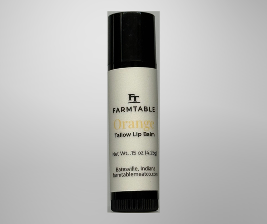 Farmtable Orange Tallow Lip Balm on a gray background