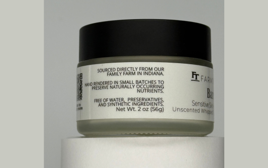 Jar of skincare product with a black lid and white label on a gray background