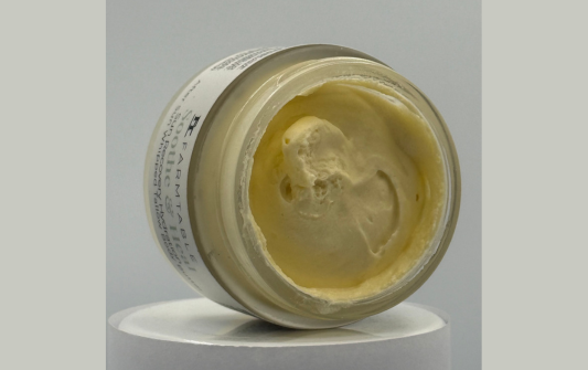 Open jar of cream on a gray background