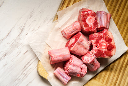 Raw oxtail on a wooden cutting board with white paper underneath